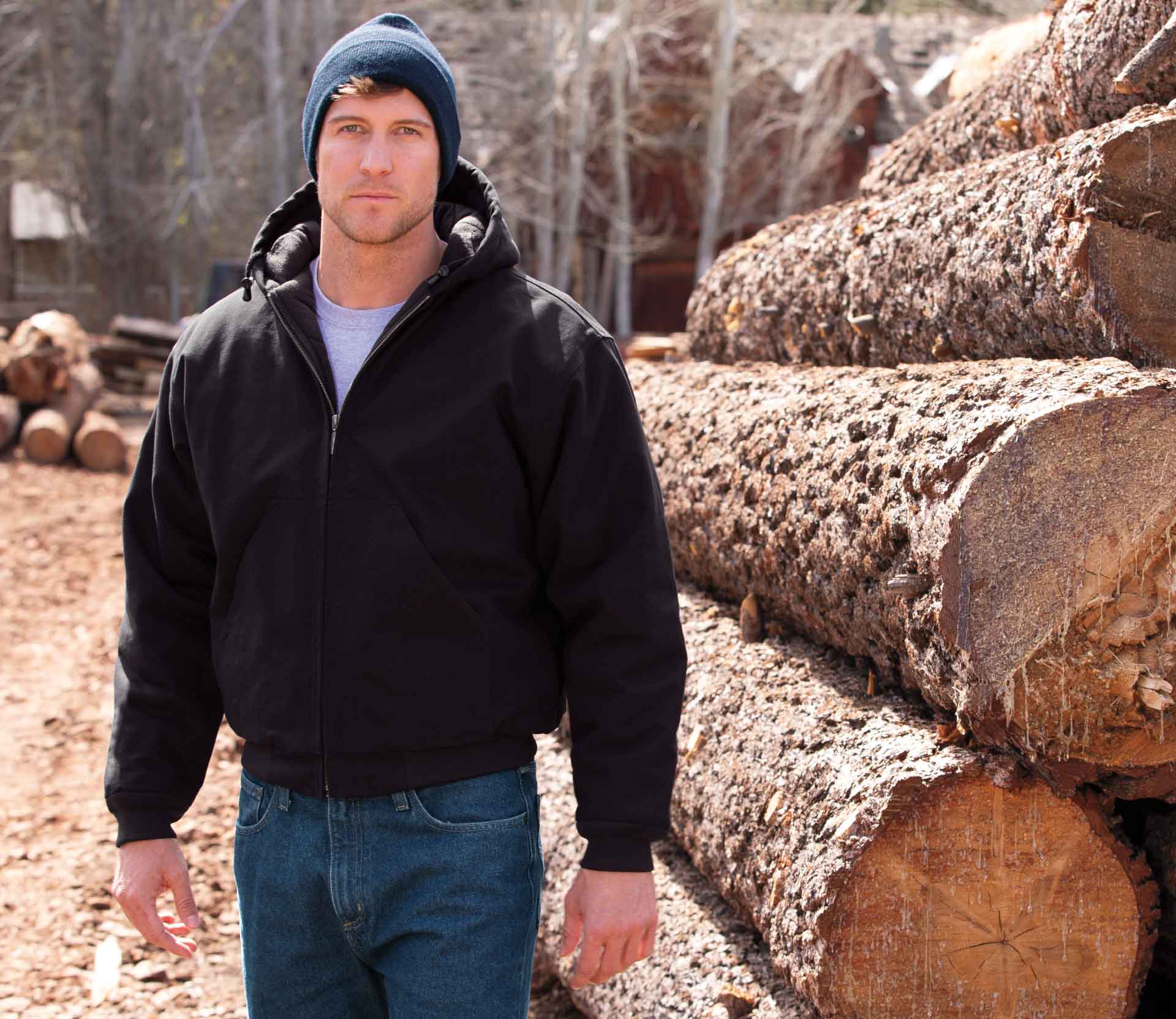 Man wearing steelguard jacket standing next to logs